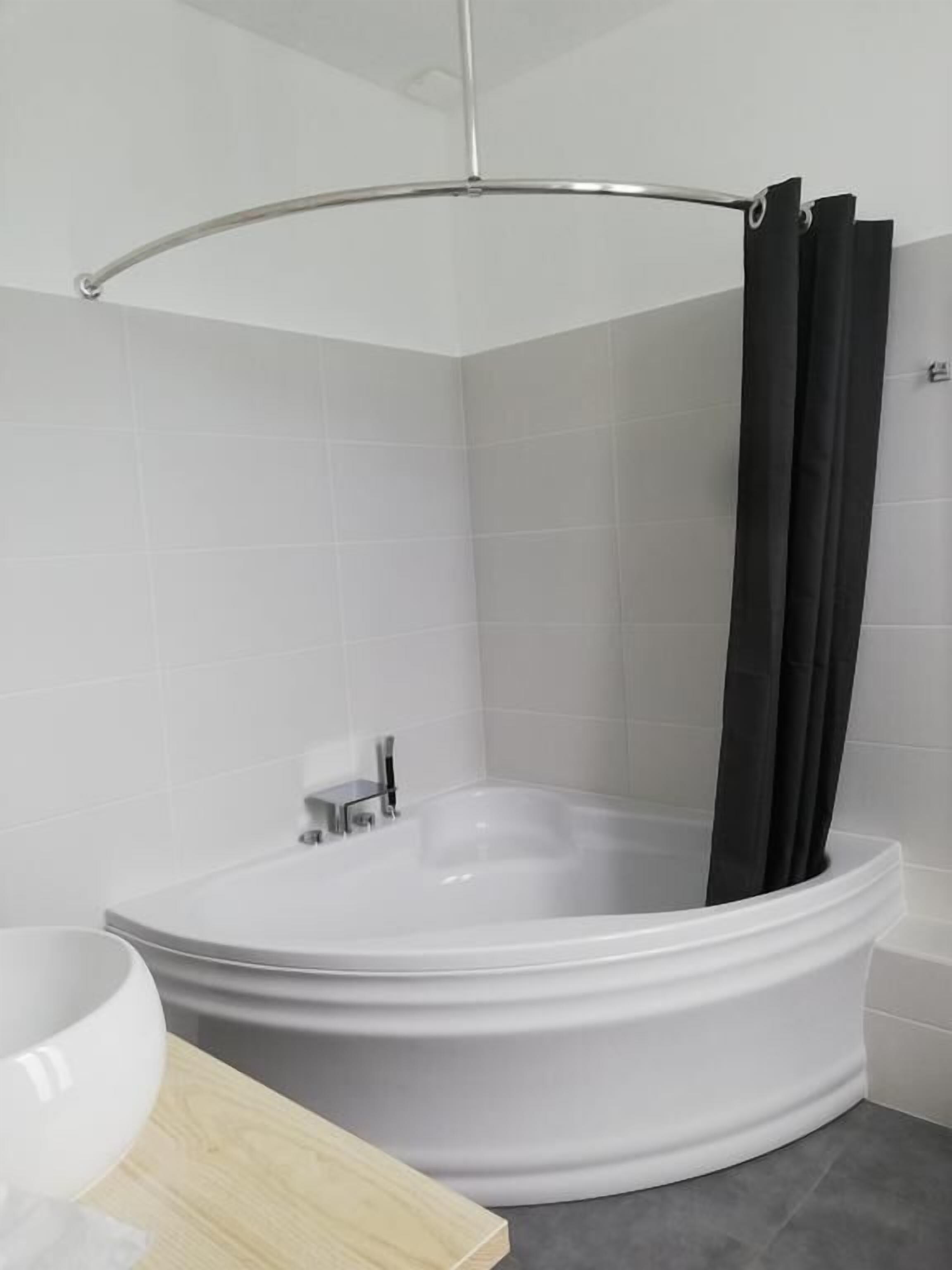 A modern bathroom with a freestanding bathtub, a shower curtain, and a toilet.
