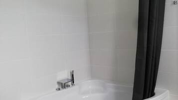 A modern bathroom with a freestanding bathtub, a shower curtain, and a toilet.