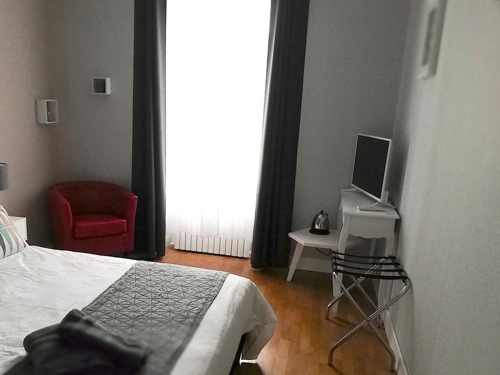 A hotel room with a bed, a desk, a chair, and a window with curtains.