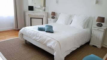 A neatly arranged bedroom with a large bed, a dresser, a mirror, and two bedside lamps.
