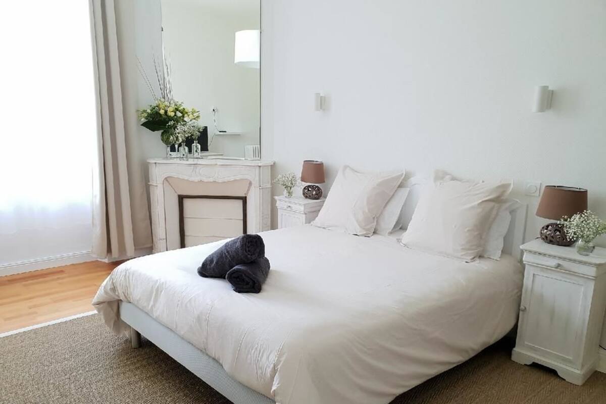 Un dormitorio con cama, mesita de noche, cómoda, espejo y ventana.