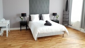 Een moderne slaapkamer met een groot bed, twee nachtkastjes, een bureau en een hanglamp.