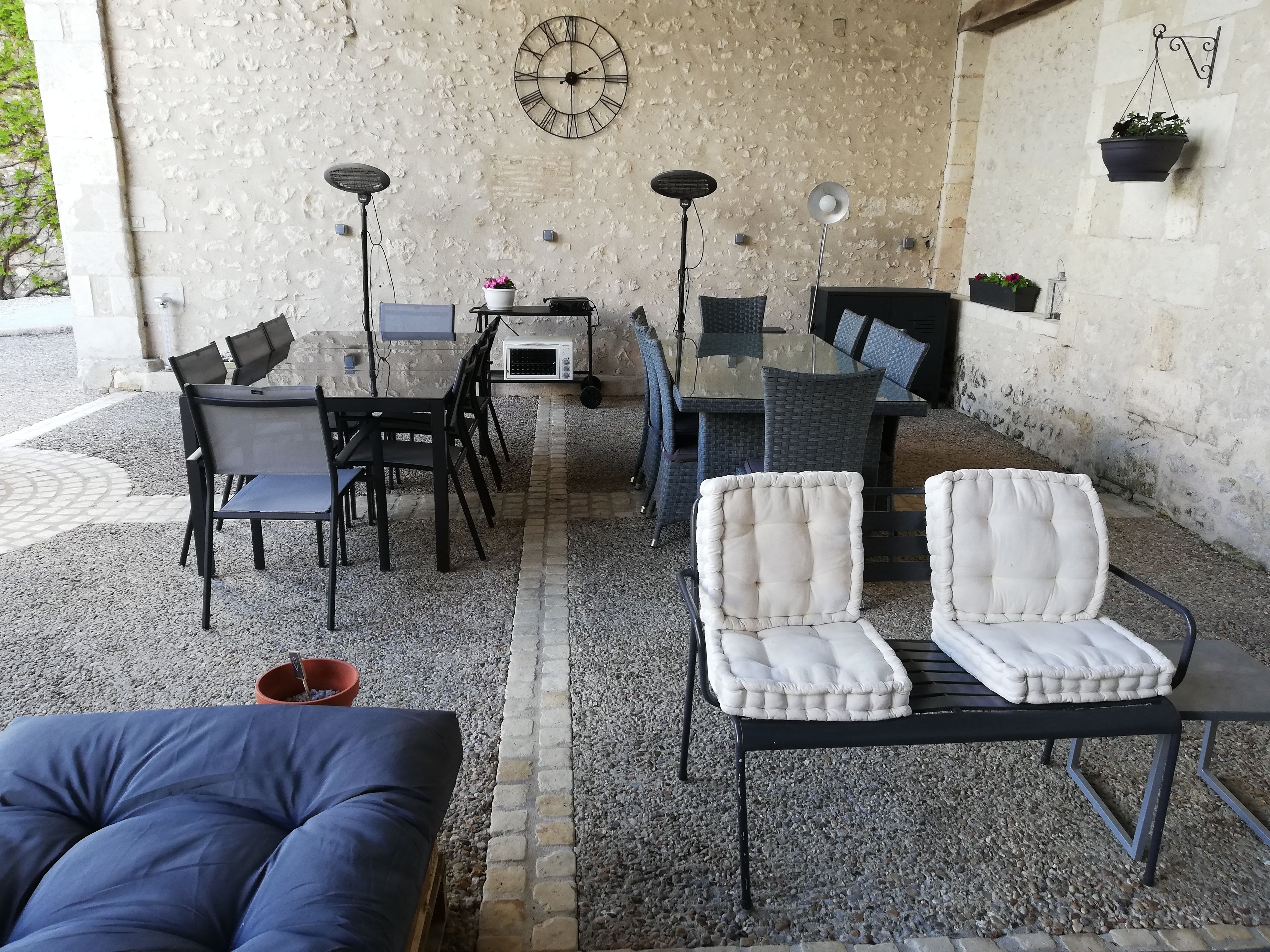 An outdoor patio with a table and chairs, a clock, and potted plants.