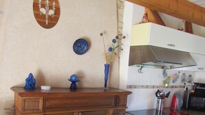 Una cocina con armarios de madera, un cubo de basura negro, una estufa y un microondas.