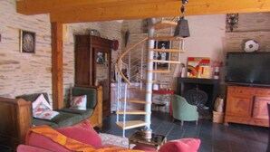 Una sala de estar acogedora con una escalera espiral, una chimenea y un televisor.