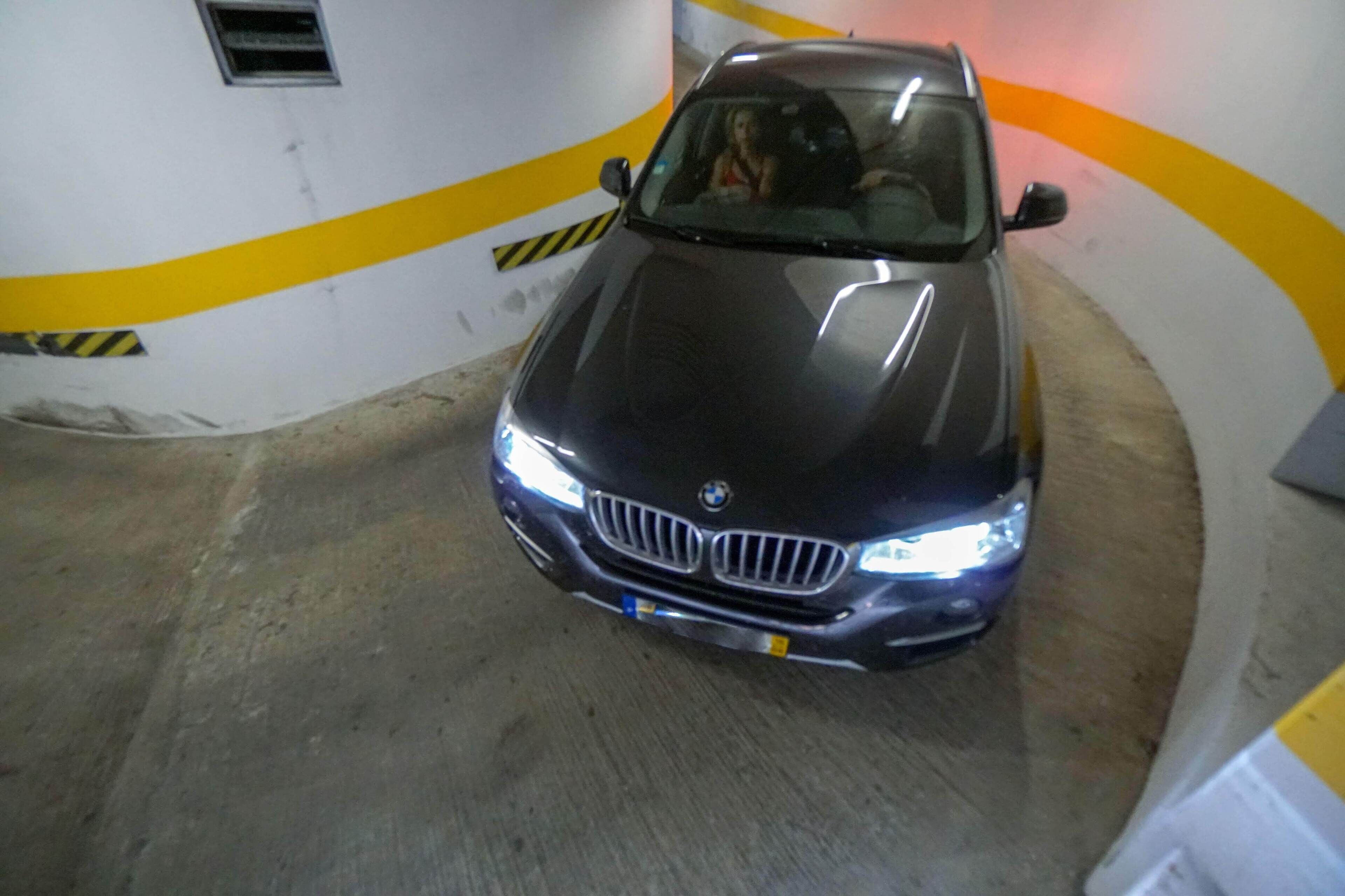 A BMW car in a parking garage with yellow and black striped walls.