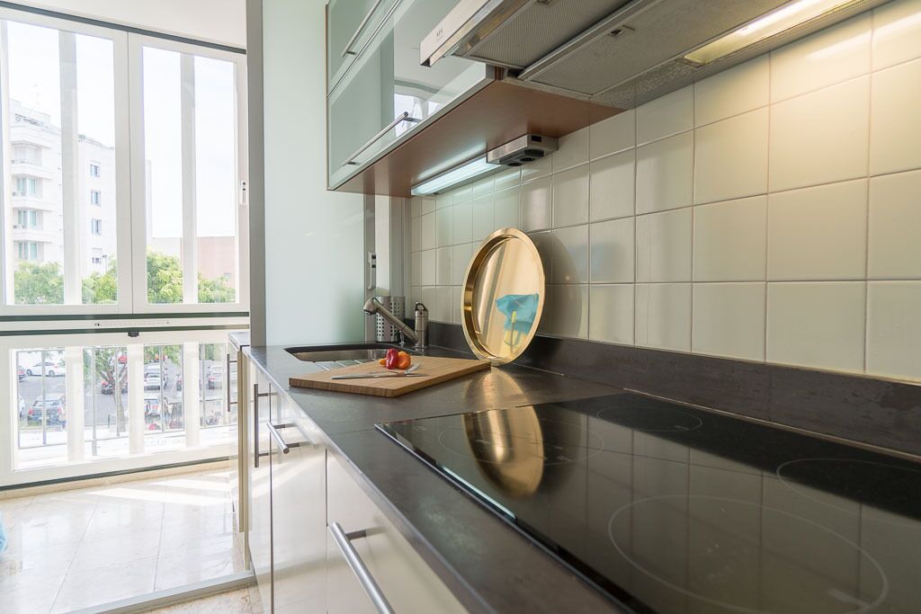 Una cocina moderna con encimera negra, electrodomésticos de acero inoxidable y una ventana que ofrece vistas al exterior.
