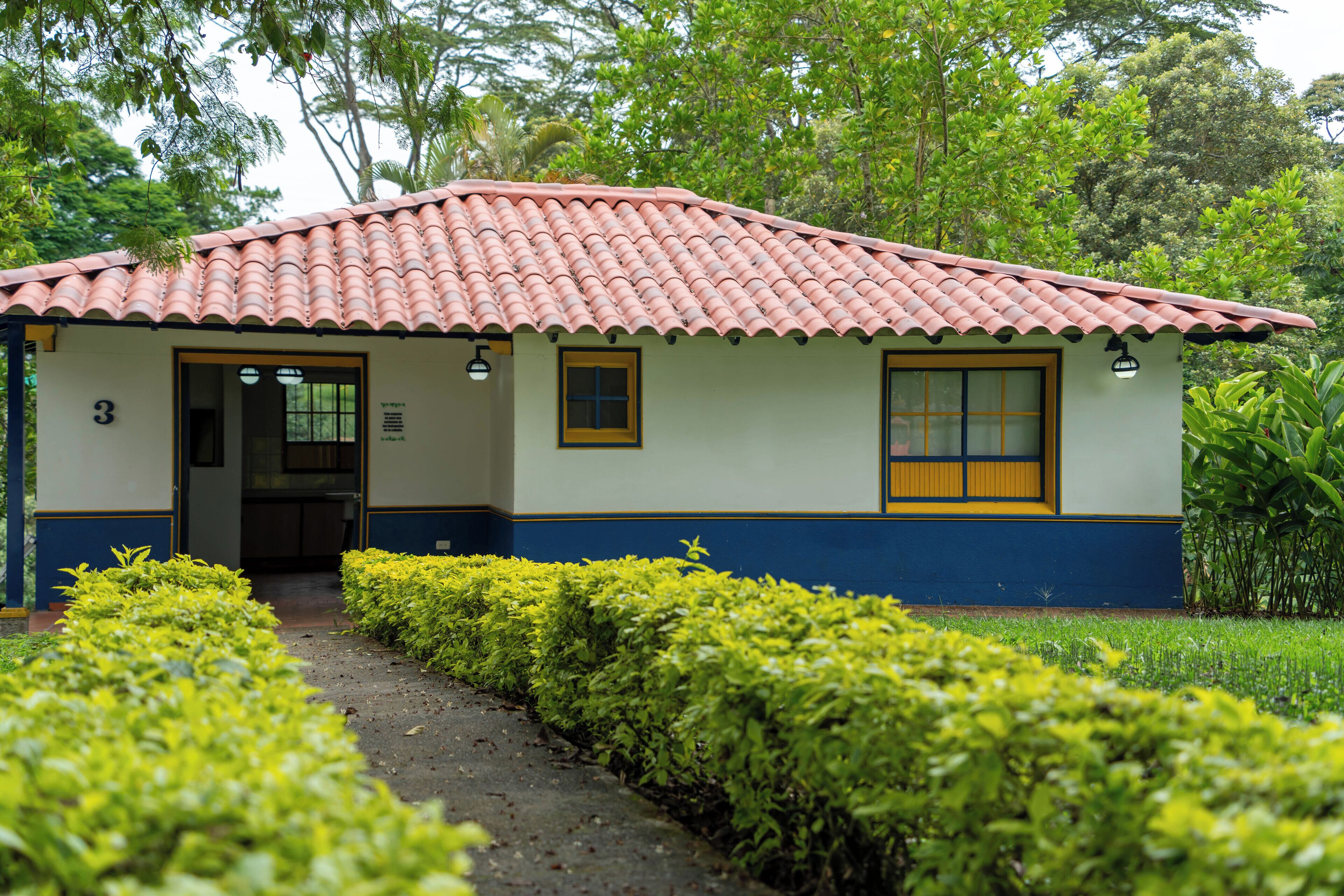 A small, single-story building with a tiled roof, numbered 3, and a pathway leading to the entrance.