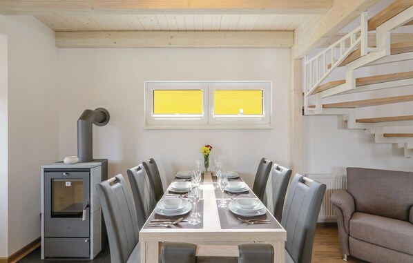 A dining area with a long table set for six, surrounded by chairs, a radiator, and a sofa. - Nice home in Thale with sauna (Thale)