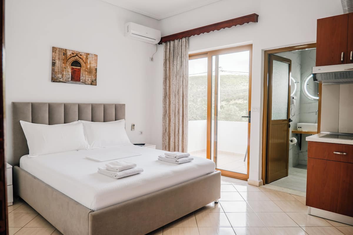 A hotel room with a bed, a bathroom with a shower, and a view of the outdoors.