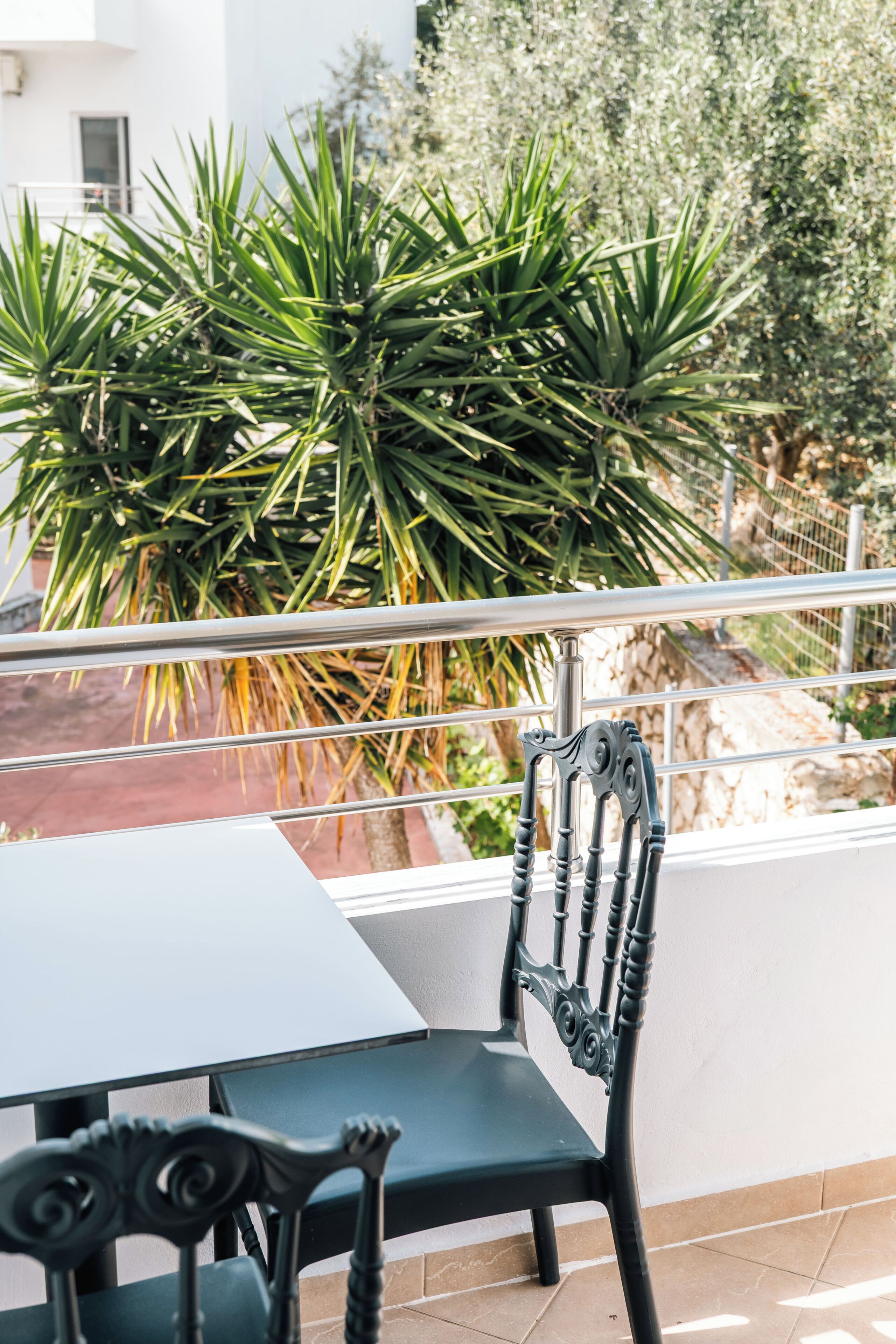 A balcony with a metal railing, a table, and a chair.