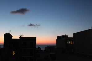 Gebäude vor einem Sonnenuntergangshimmel als Silhouette.
