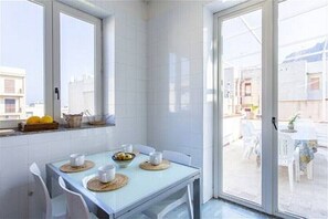 Ein Essbereich mit Tisch für zwei Personen, ein Fenster mit Stadtblick und ein Balkon mit Sitzgelegenheit.