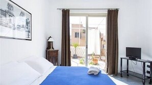 Een hotelkamer met een bed, een televisie en een balkon met gordijnen.