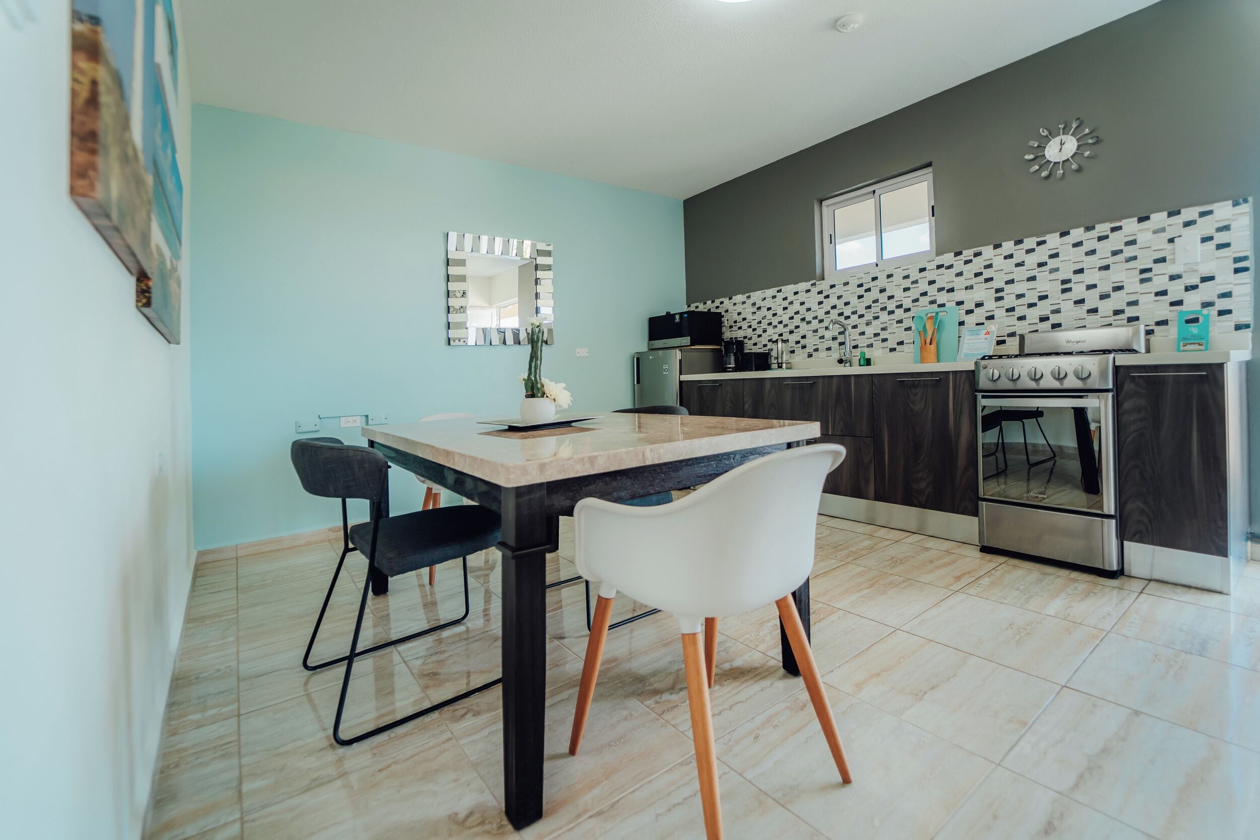 Una cocina moderna con encimera de mármol, armarios oscuros y salpicadero de azulejos.