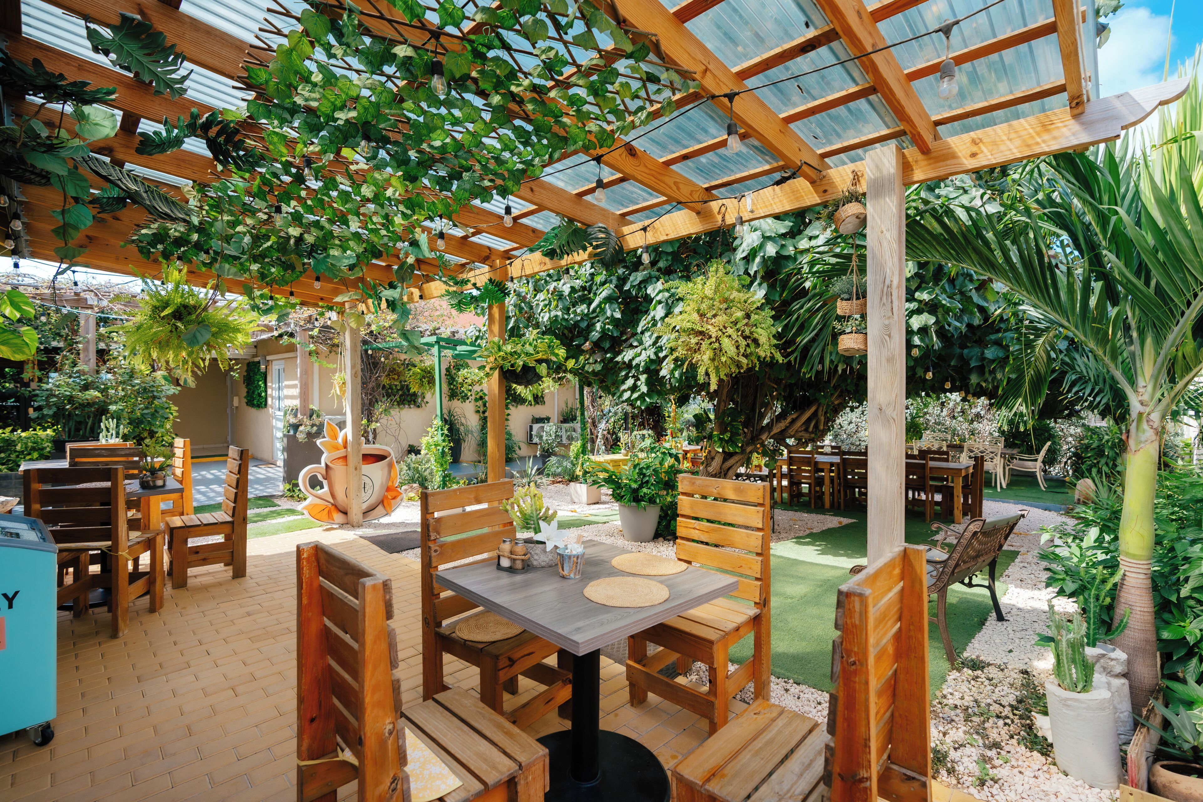 An outdoor patio area with wooden furniture, a table, and hanging plants.