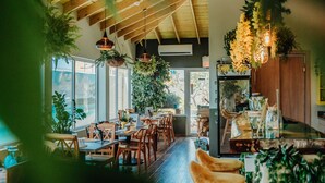 A restaurant with wooden beams, large windows, and hanging plants. - Hotel RH Boutique Aruba (Oranjestad)