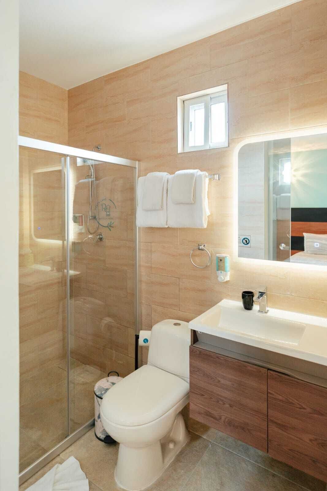 Ein modernes Badezimmer mit Duschkabine aus Glas, Toilette, Waschbecken mit Spiegel und Handtuchhalter.