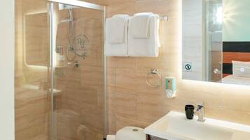 Ein modernes Badezimmer mit Duschkabine aus Glas, Toilette, Waschbecken mit Spiegel und Handtuchhalter.