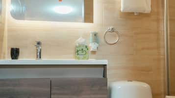 A modern bathroom with a sink, mirror, toilet, and shower.
