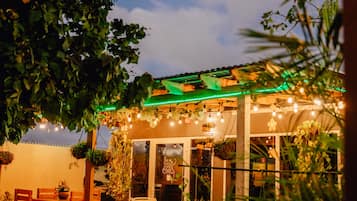 Un área de patio al aire libre con una pérgola, luces colgantes y asientos.