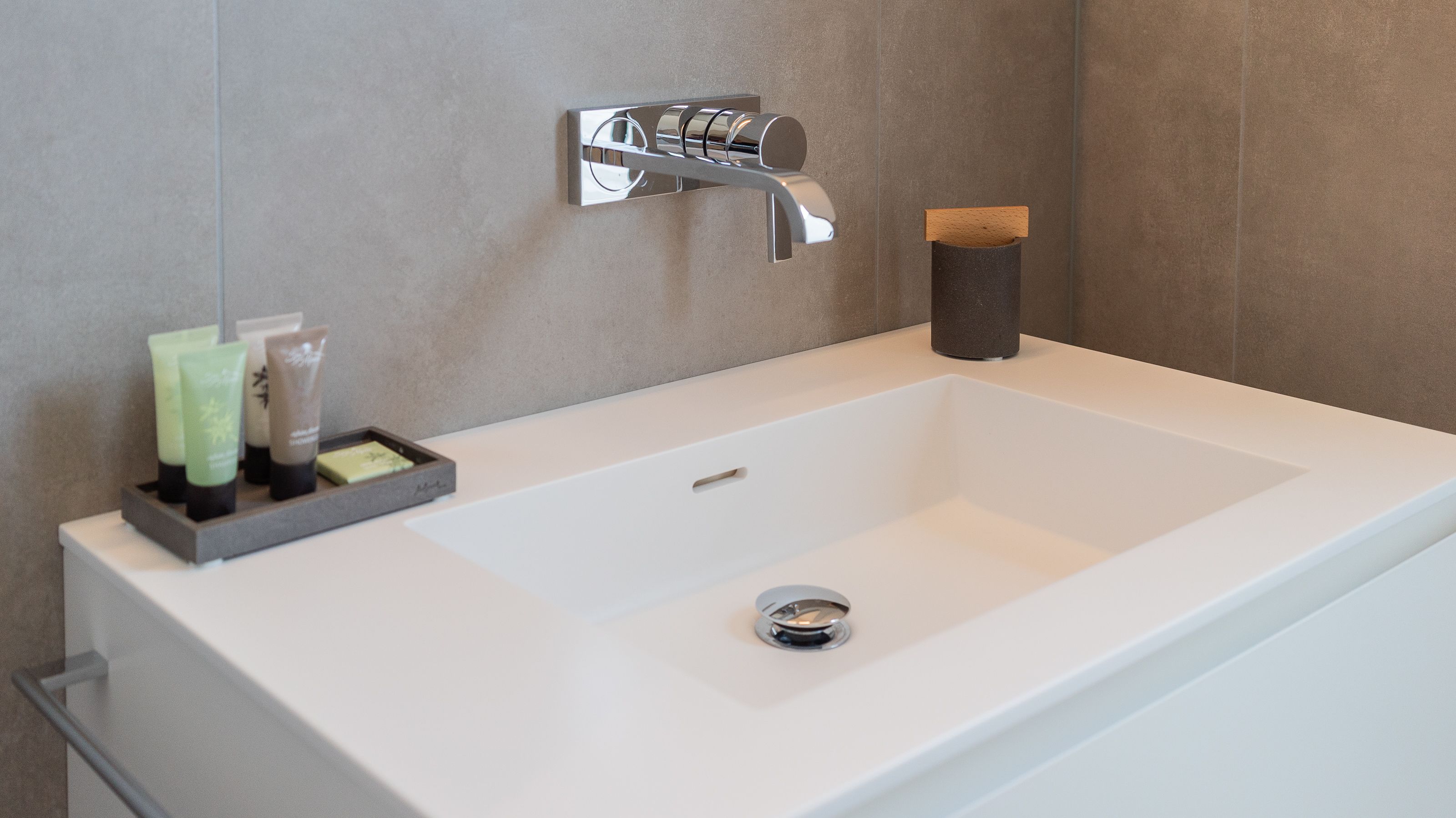 Ein modernes Badezimmer mit einem weißen Waschbecken, einem Chromarmaturenset und einer Seifenschale.