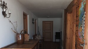 Un pasillo de madera con un tapete a rayas, un armario de madera rústica y una puerta con un cuadro colorido.