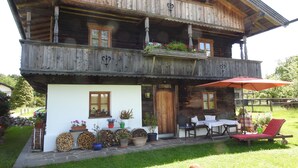 Una cabaña de madera con balcón, mobiliario exterior y un jardín cuidado.