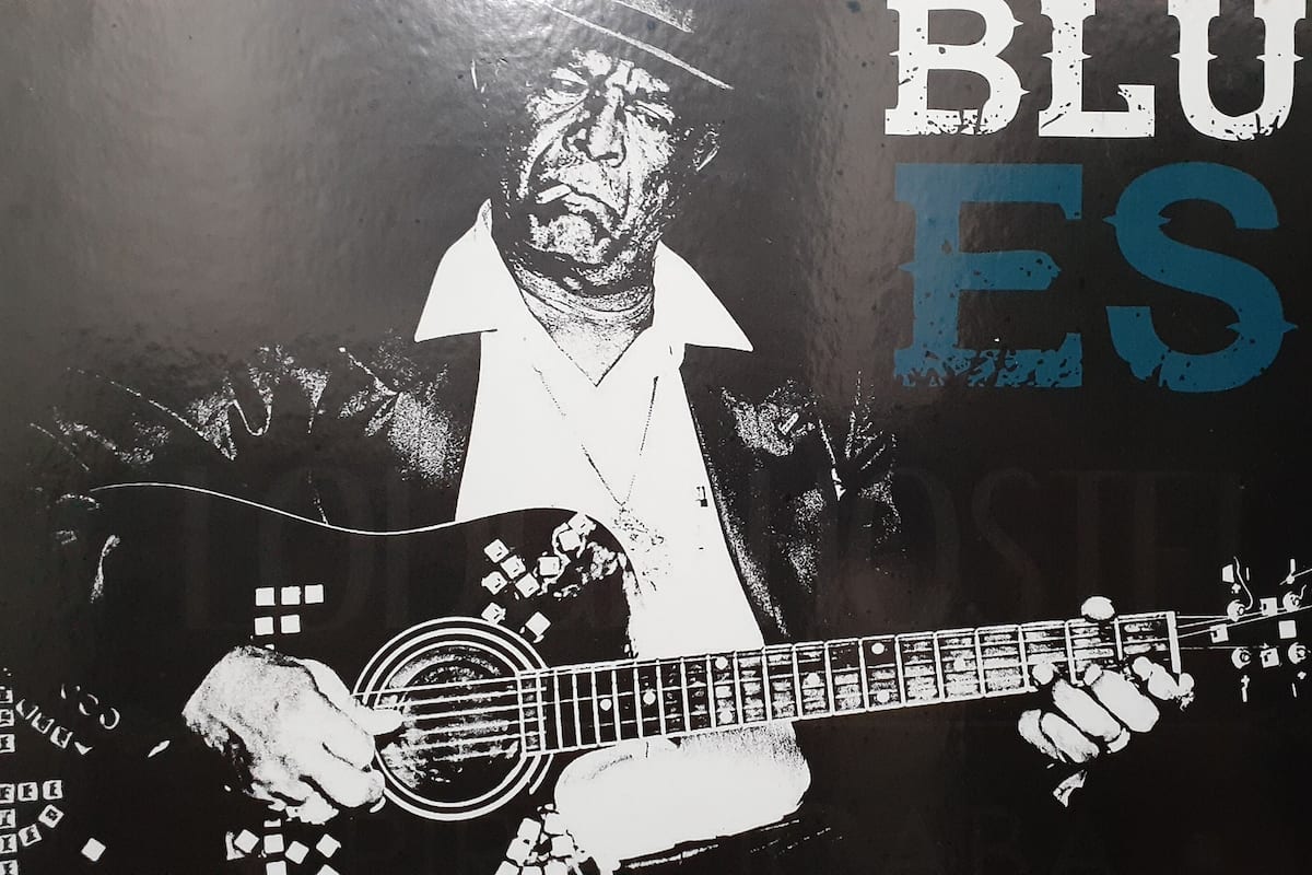 A person playing a guitar with the text "BLUES" and "John" visible.