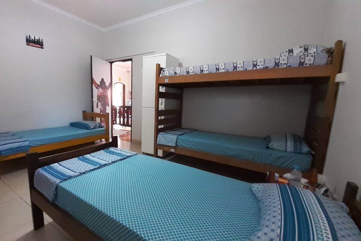 A dormitory room with bunk beds, a small desk, and a chair.