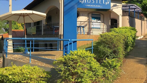 Un hostal con un letrero azul e icono de lámpara blanca, indicando un establecimiento de hospedaje en Piracicaba.