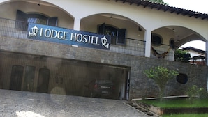 Un edificio con un cartel que dice "Lodge Hostel" y un coche estacionado adelante.