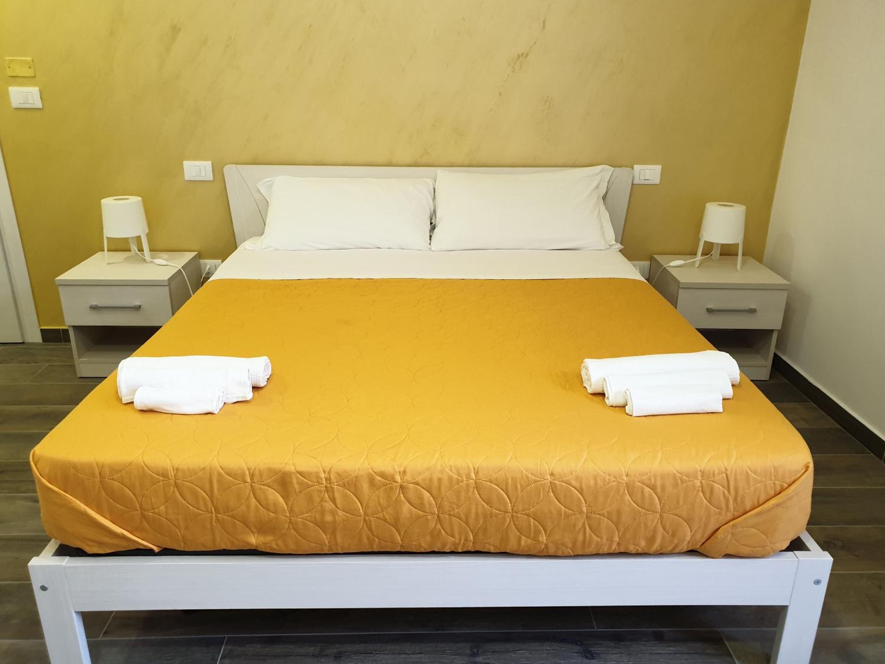 Une chambre d’hôtel avec un lit, deux tables de chevet et deux lampes.