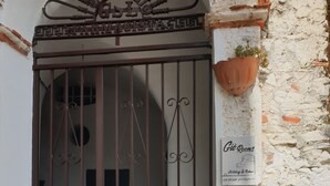 A gated entrance with a decorative metal arch, a sign for 'Giò Rooms' advertising holidays and relaxation, and potted plants on the steps. - Giò Rooms (Scalea)