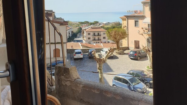 A view from a window overlooking a street with parked cars and buildings. - Giò Rooms (Scalea)