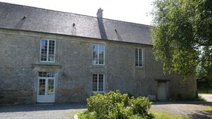 Un bâtiment en pierre de deux étages, avec une allée gravillonnée et un petit jardin.