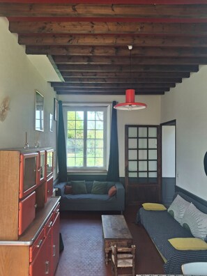 A room with a wooden ceiling, a sofa, a table, and a cabinet. - Charming house in a quiet (BARBEVILLE)