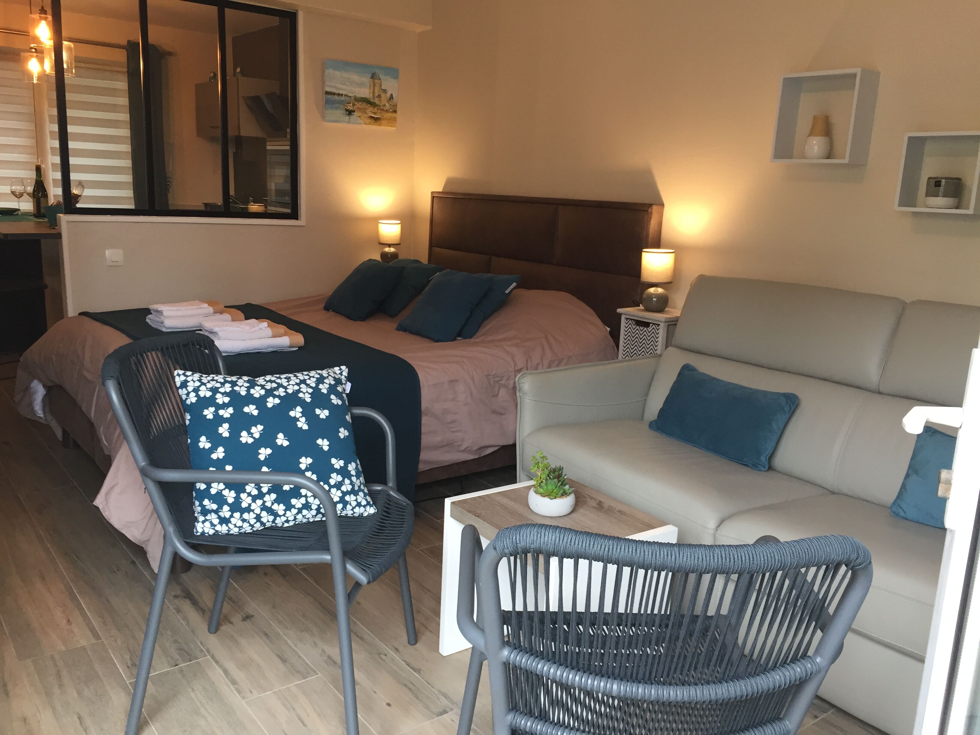 Ett mysigt rum med en säng, en soffa, en fåtölj och ett litet bord med en växt.
