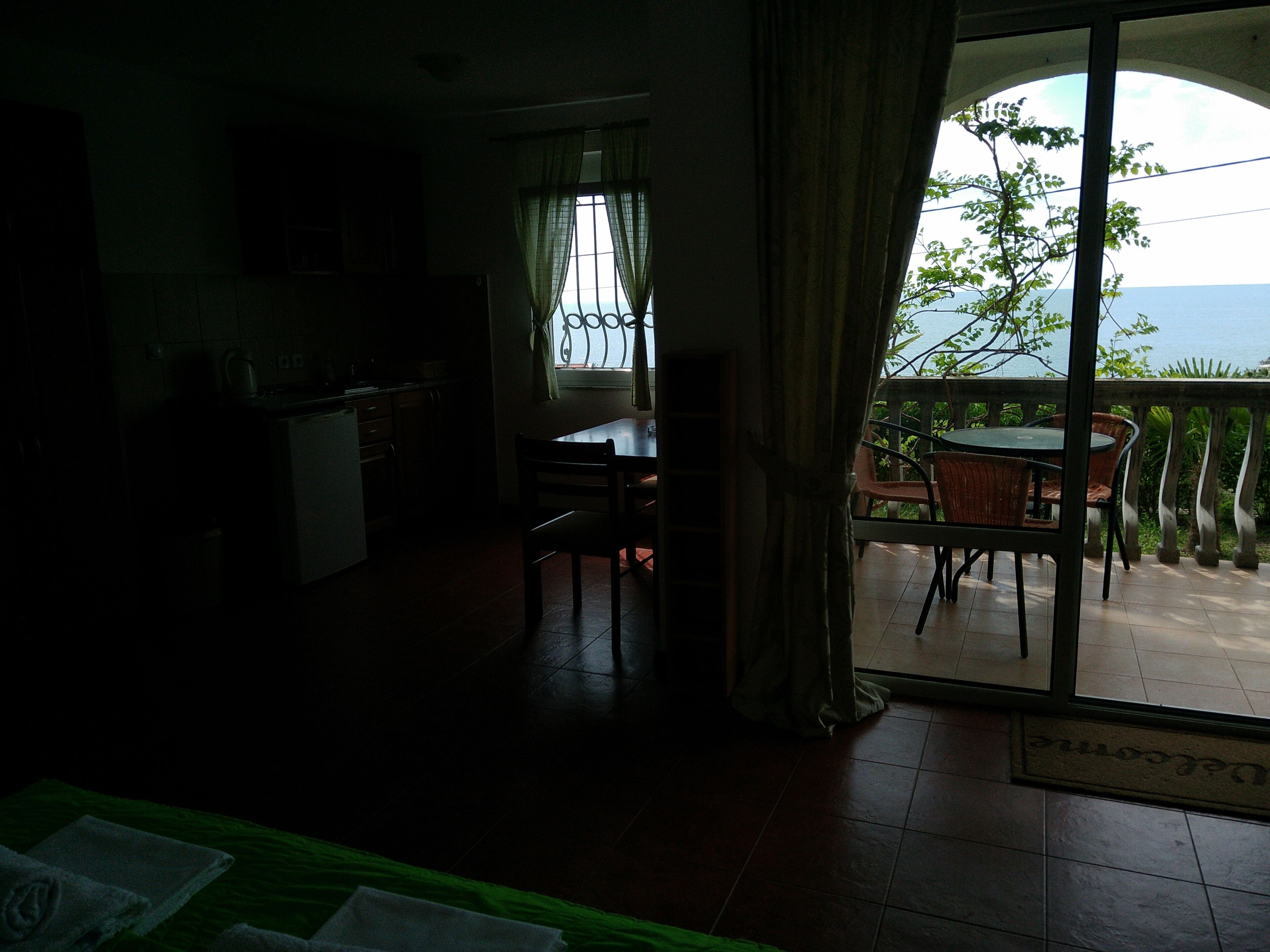 Ein Zimmer mit Essbereich, einer Küche und einem Balkon mit Meerblick.