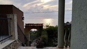 A stone-paved patio with a view of the sea, a pergola, and a stone wall. - Majero Apartments (Utjeha)