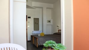Una habitación de hotel con una cama, una mesita con una planta y una silla blanca.