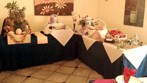 Montaje de bufé con mesas cubiertas, un cuadro floral y un cartel en la pared.