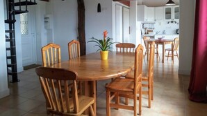 Ein Essbereich mit Holztisch und -stühlen, einem Blumentopf und einer Treppe, die in einen anderen Raum führt.
