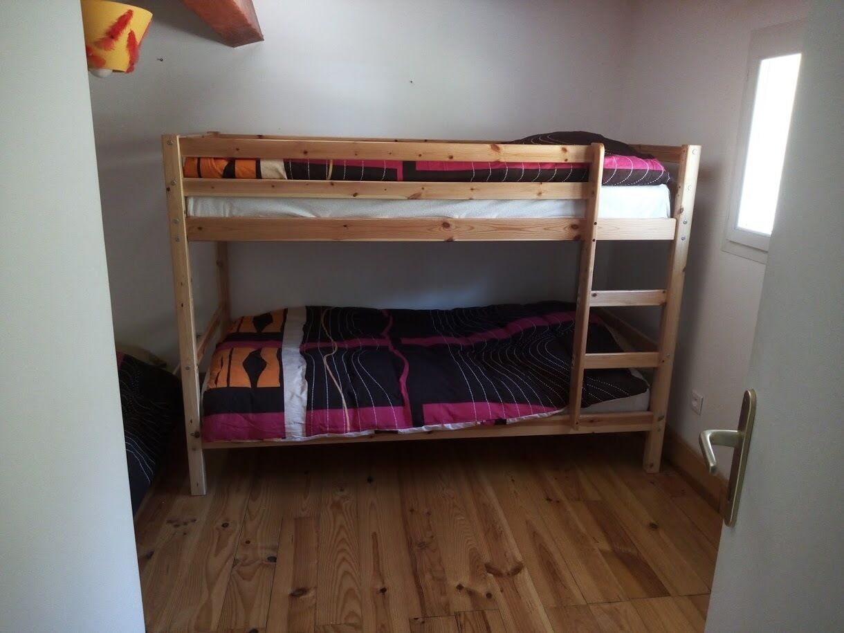 Un lit superposé avec une structure en bois et une couverture colorée.