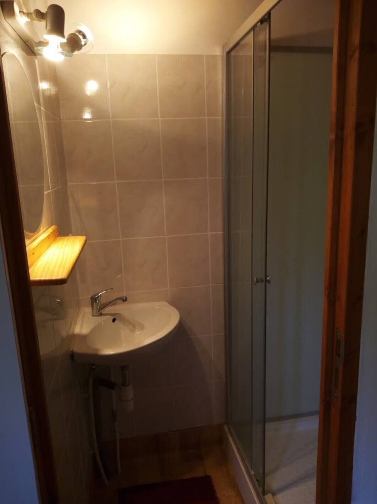 Ein kleines Badezimmer mit Waschbecken, Spiegel und Dusche.