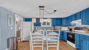 Une cuisine avec des meubles de couleur bleue, un réfrigérateur blanc, un four à micro-ondes et une cuisinière.