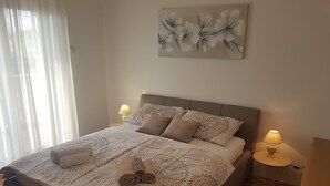 Una cama bien hecha con ropa de cama estampada, dos lámparas de noche y una obra de arte floral en la pared.