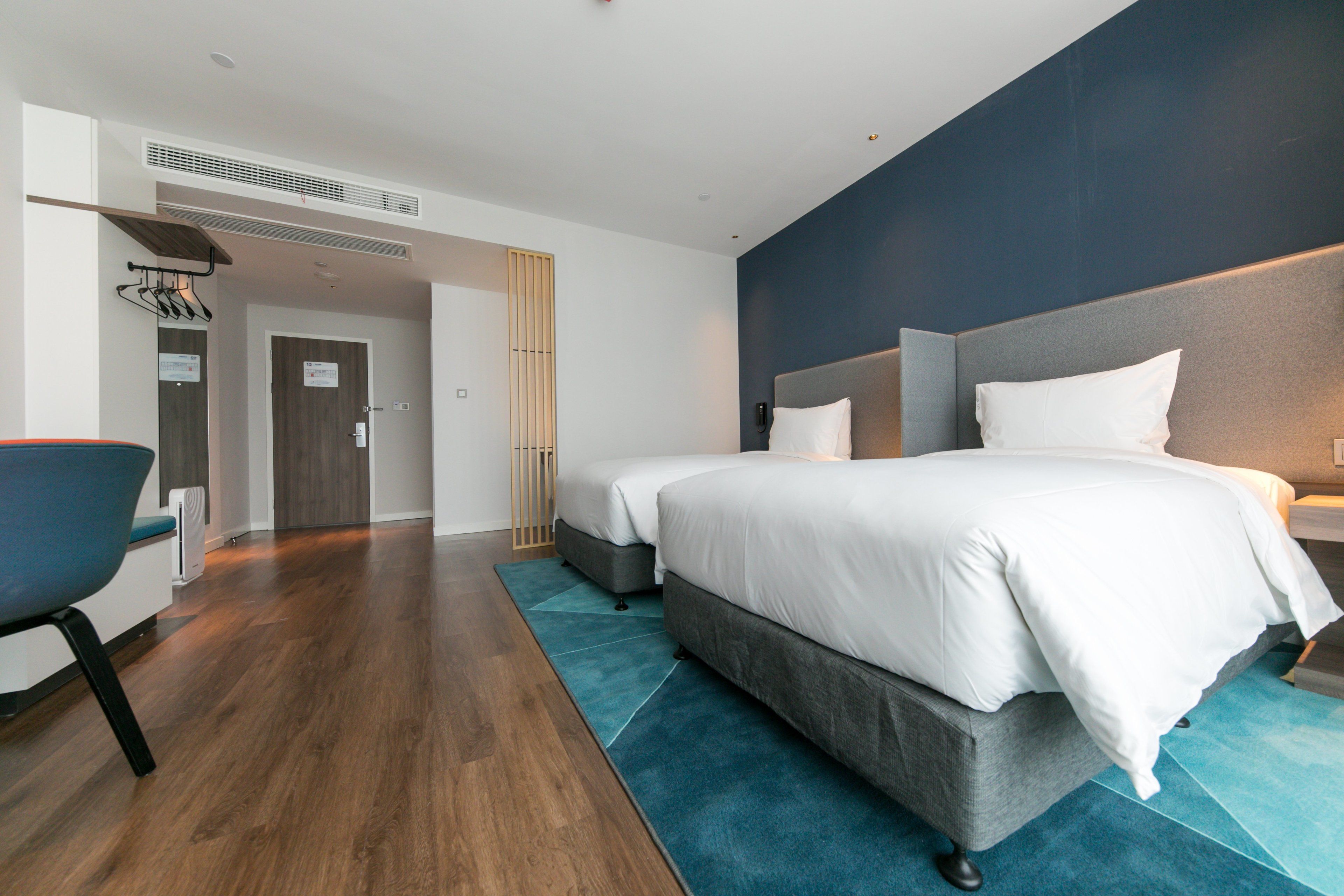 A modern hotel room with a large bed, a desk, and a chair.