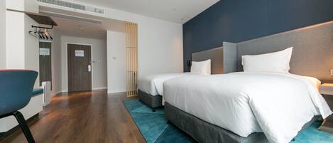 Une chambre d’hôtel moderne avec un grand lit, un bureau et une chaise.