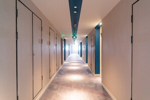 A hotel corridor with doors on both sides, a patterned carpet, and a ceiling with recessed lighting. - Holiday Inn Express Shanghai Tangzhen by IHG (Shanghai)